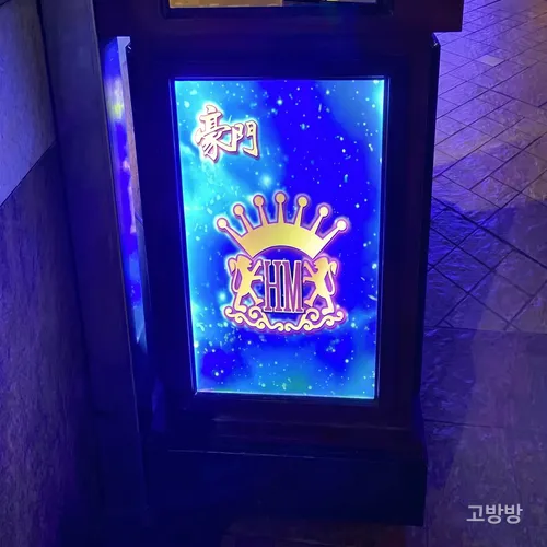 왕관 로고가 푸르게 빛나는 파밀리아 노브레 입구 라이트박스 간판, 마카오