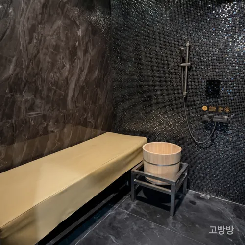 검은 모자이크 타일 샤워월과 나무 물통이 놓인 만하오 스파 세신실, 마카오